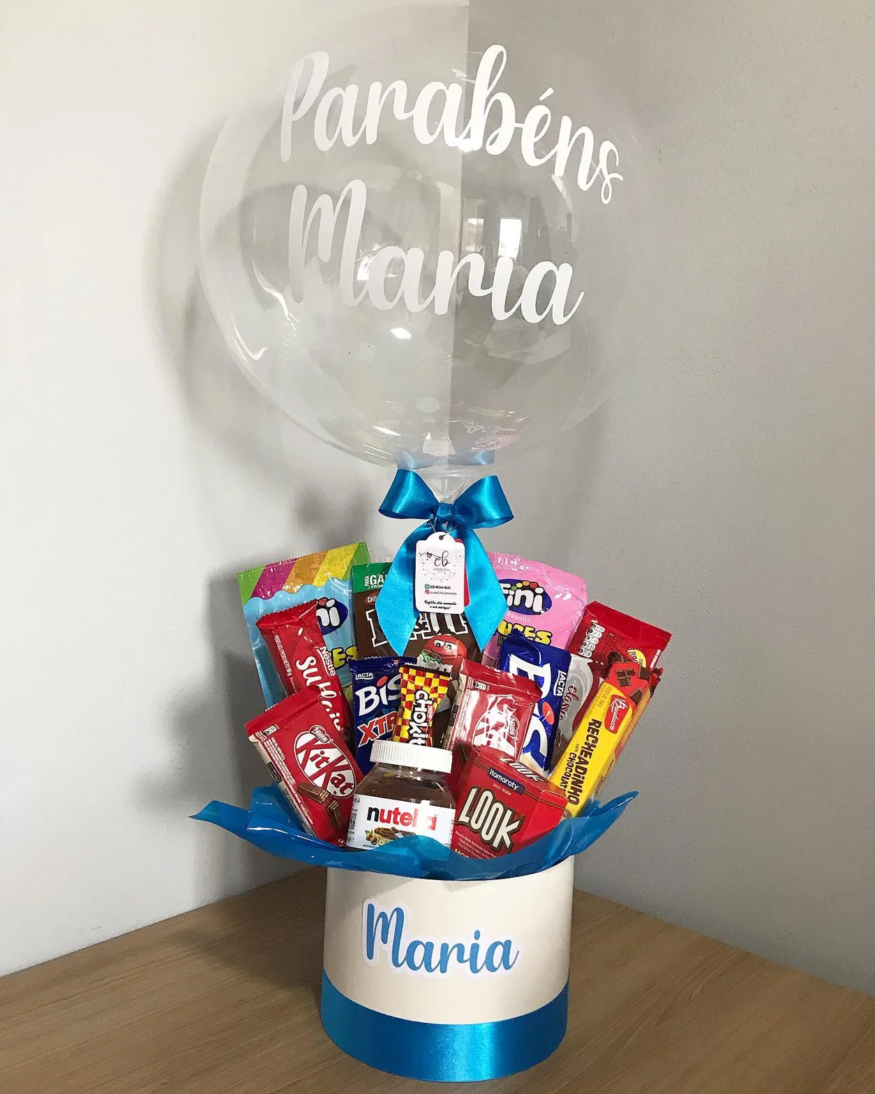 Caixa com balão transparente escrito Parabéns Maria e chocolates dentro